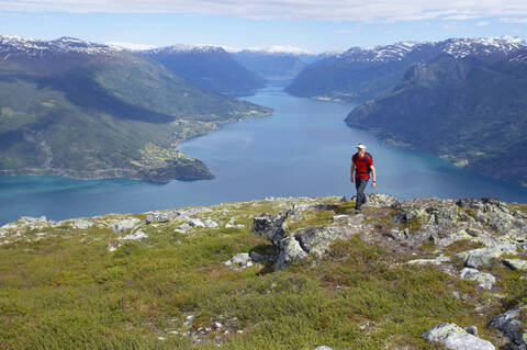 Norwegen, Lustrafjord, Mann wandert über Klippenlinie, lizenzfreies Stockfoto