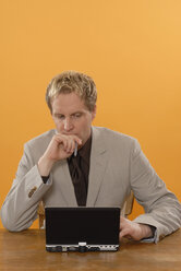 Geschäftsmann am Laptop sitzend, nachdenklich, Porträt - KJF00030