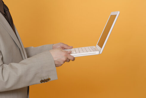 Businessman holding laptop, middle section - KJF00028