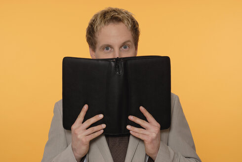 Man hiding face behind organizer - KJF00023