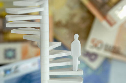 Figurine on spiral stair, money in background - ASF03851