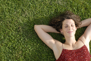 Junge Frau auf Rasen liegend, Augen geschlossen, lächelnd, Blick von oben, Porträt - KJF00061