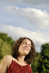 Young woman sunbathing, eyes closed, smiling, portrait - KJF00059