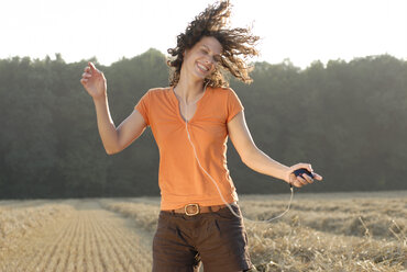 Junge Frau auf einem Feld, tanzend, MP3-Player hörend - KJF00052