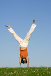 Junge Frau macht Handstand auf der Wiese - KJF00042