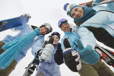 Italy, South Tyrol, Four people in winter clothes, thumbs up, low angle view - WESTF11319