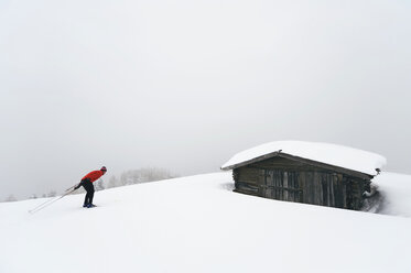 Italien, Südtirol, Mann beim Skilanglauf, Hütte im Hintergrund - WESTF11293