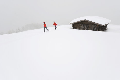 Italien, Südtirol, Paar beim Langlaufen neben der Hütte - WESTF11291