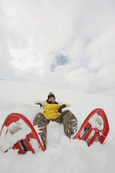 Italien, Südtirol, Junge Frau mit Schneeschuhen im Schnee liegend - WESTF11240