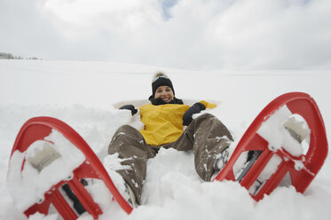 Italien, Südtirol, Junge Frau mit Schneeschuhen im Schnee liegend - WESTF11239