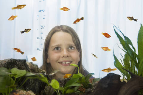 Girl (8-9) watching fish, view through fish tank stock photo