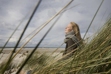 Deutschland, Schleswig Holstein, Amrum, Junge Frau auf grasbewachsener Sanddüne, Augen geschlossen - RBF00021