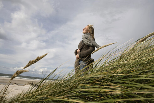 Deutschland, Schleswig Holstein, Amrum, Junge Frau auf grasbewachsener Sanddüne - RBF00020