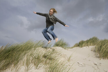 Deutschland, Schleswig Holstein, Frau in Sanddünen, springend - RBF00019