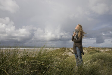 Germany, Schleswig Holstein, Amrum, Young woman on grassy sand dune - RBF00017