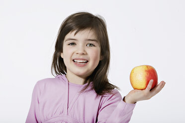Mädchen (4-5) hält einen Apfel, lächelnd, Porträt, Nahaufnahme - LDF00608