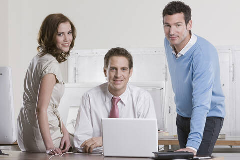 Deutschland, München, Mitarbeiter zusammen im Büro, lächelnd, Porträt, lizenzfreies Stockfoto