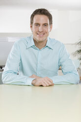 Germany, Munich, young man in office, arms crossed, smiling, portrait, close-up - LDF00619