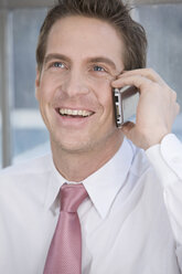 Germany, Munich, business man using mobile phone, smiling, portrait - LDF00617