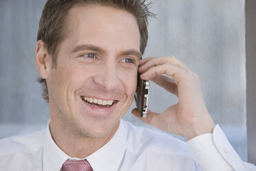 Germany, Munich, business man using mobile phone, smiling, portrait - LDF00616