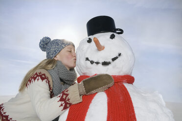 Deutschland, Bayern, München, Junge Frau küsst Schneemann, Porträt - RBF00032