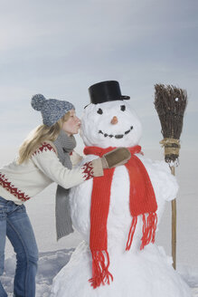 Deutschland, Bayern, München, Junge Frau küsst Schneemann, Porträt - RBF00031