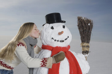 Deutschland, Bayern, München, Junge Frau küsst Schneemann, Porträt - RBF00030