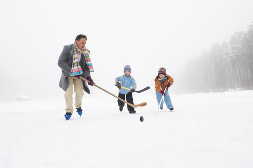 Italien, Südtirol, Seiseralm, Vater und Kinder (4-5) spielen Eishockey - WEST11741