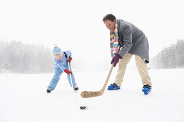 Italy, South Tyrol, Seiseralm, Father and son (4-5) playing ice hockey - WEST11738