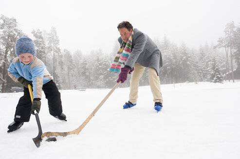 Italien, Südtirol, Seiseralm, Vater und Sohn (4-5) spielen Eishockey - WEST11737