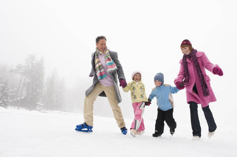 Italien, Südtirol, Seiseralm, Familie hält sich an den Händen, Schlittschuhlaufen, lizenzfreies Stockfoto