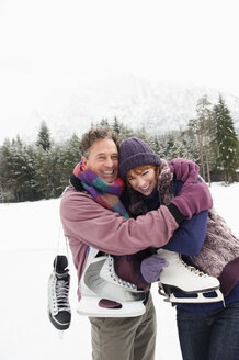 Italien, Südtirol, Seiseralm, Ehepaar mit Schlittschuhen, umarmend, lächelnd, Porträt - WEST11699