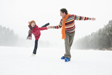 Italy, South Tyrol, Seiseralm, Woman ice skating on one leg, Man assisting - WEST11687