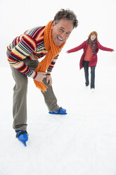 Italy, South Tyrol, Seiseralm, Woman ice skating, man in foreground, laughing, portrait - WEST11681