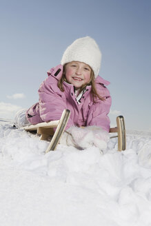 Germany, Bavaria, Munich, Girl (6-7) lying on sledge, smiling, portrait - RBF00070