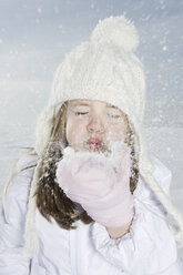 Deutschland, Bayern, München, Mädchen (4-5) bläst Schnee von der Hand, Augen geschlossen, Porträt - RBF00053