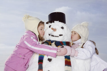 Deutschland, Bayern, München, Zwei Mädchen (4-5) (8-9) küssen Schneemann, Augen geschlossen, Porträt - RBF00042