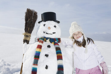 Deutschland, Bayern, München, Mädchen (8-9) neben Schneemann stehend, Porträt - RBF00038