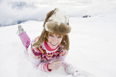 Italien, Südtirol, Seiseralm, Frau im Schnee liegend, lächelnd, Porträt, Nahaufnahme - WEST11659