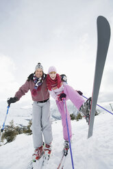 Italy, South Tyrol, Seiseralm, Couple standing on skis, lifting leg - WEST11633