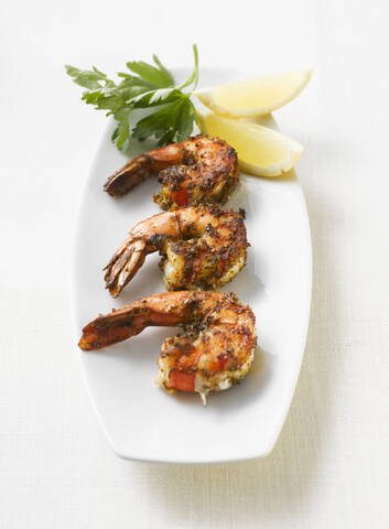 Gegrillte Shrimps, Petersilie und Zitronenscheiben auf einer Platte, Ansicht von oben, lizenzfreies Stockfoto