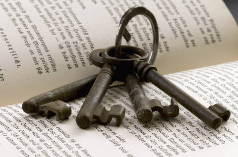 Schlüssel am Schlüsselbund auf offenem Buch liegend, lizenzfreies Stockfoto