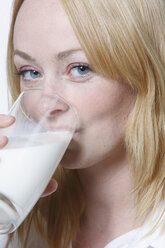 Young woman drinking glass of milk, portrait - KSWF00517