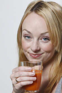 Junge Frau mit Glas Karottensaft in der Hand, Porträt - KSWF00492