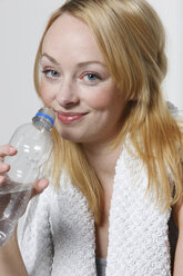 Junge Frau hält Wasserflasche, Handtuch um den Hals - KSWF00491