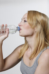 Junge Frau trinkt aus einer Wasserflasche, Porträt - KSWF00490