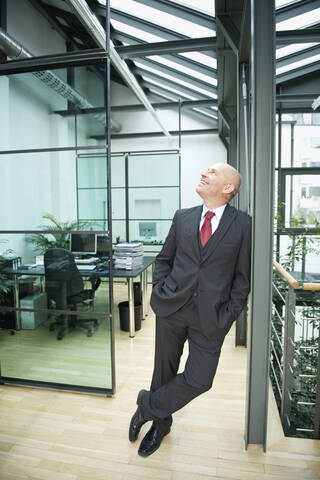 Deutschland, München, Geschäftsmann im Büro stehend, Hände in den Taschen, lizenzfreies Stockfoto