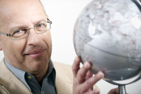 Businessman holding globe, portrait - WESTF11779