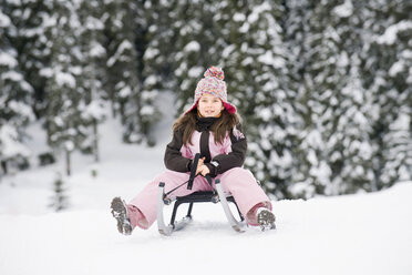 Cute little girl sitting in snow in winter stock photo