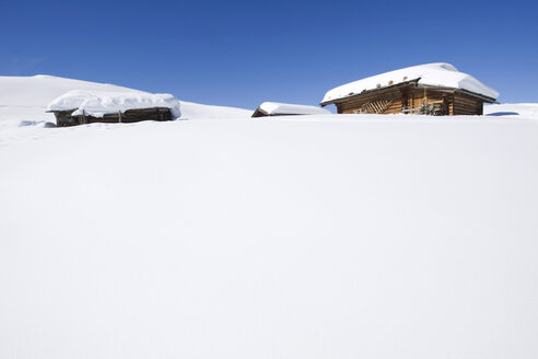 Italien, Südtirol, Seiseralm, Blockhütten in verschneiter Landschaft - WESTF11447